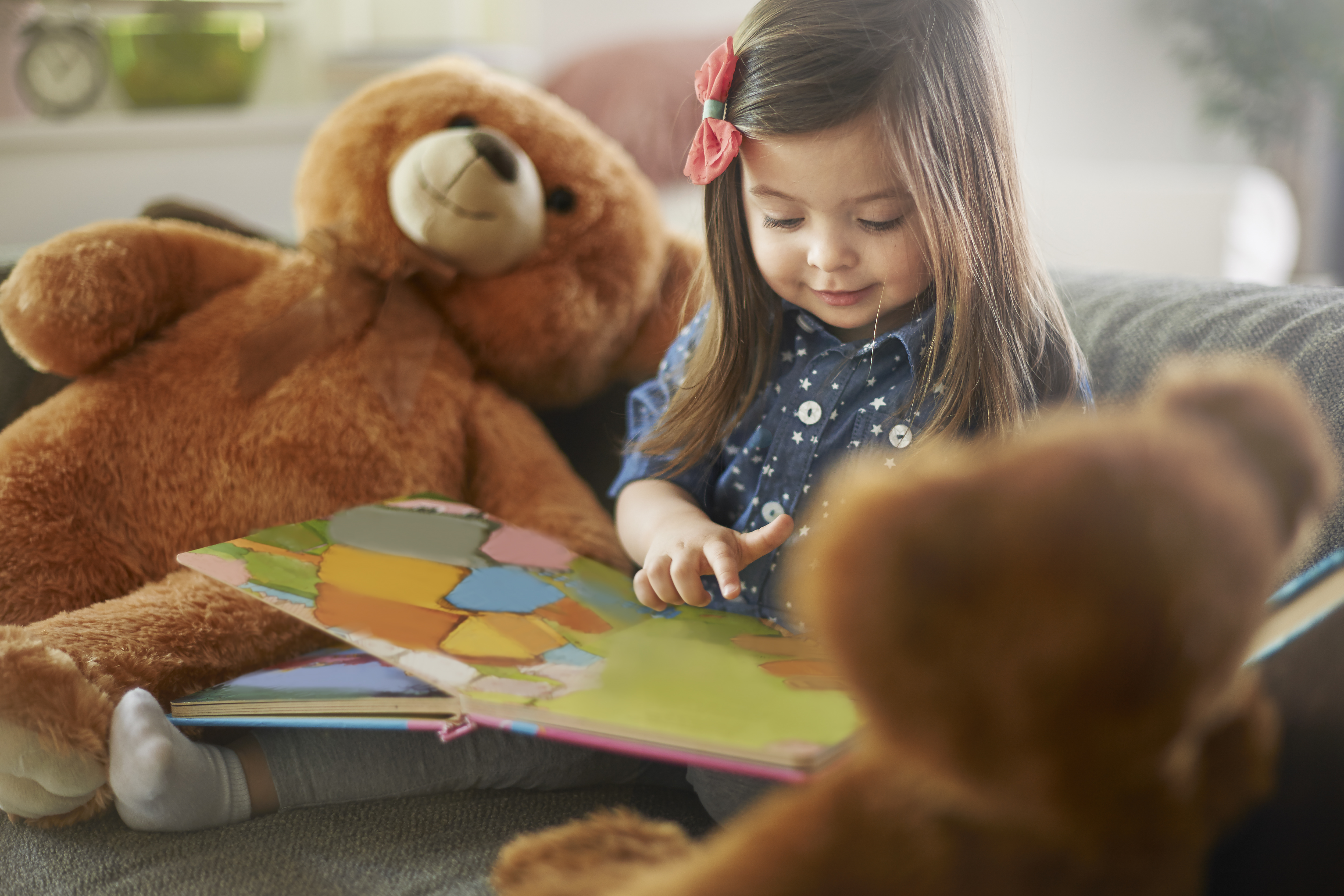 menina lendo um livro com seus ursinhos de pelucia
